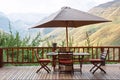 Table and chairs under umbrella on terrace against awesome mount