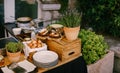 Table with chicken eggs, wooden cutting board with cheese and prosciutto and lavender flowerpots.