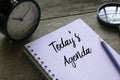 Table clock,magnifying glass,pencil and notebook written with Today's Agenda on wooden background Royalty Free Stock Photo