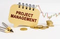 On the table are coins, a pen, a graph and a sign with the inscription - PROJECT MANAGEMENT Royalty Free Stock Photo