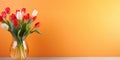 Table with colorful tulips in glass vase against orange wall. Interior background with copy space Royalty Free Stock Photo