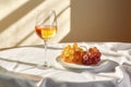 On a table covered with white fabric, a crystal glass with amber wine sits, a beautiful shade of orange. Soft sunlight and shadows