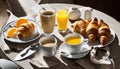 A table with a croissant, orange, coffee, and juice