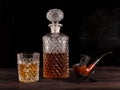 On the table are a decanter and a glass of whiskey and a smoking pipe Royalty Free Stock Photo