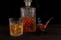 On the table are a decanter and a glass of whiskey and a smoking pipe Royalty Free Stock Photo