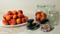 On the table is a dish with peaches, jars for home canning, lids for jars and a key for canning