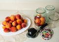 On the table is a dish with peaches, jars for home canning, lids for jars and a key for canning