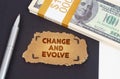 On the table are dollars, a pen and a cardboard sign with the inscription - CHANGE AND EVOLVE