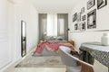 Table with doted tablecloth in bright bedroom interior with white empty wall, mirror and king size bed with grey bedding and Royalty Free Stock Photo