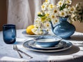 table with elegant vase with flowers and ceramic plates in white-blue colors Royalty Free Stock Photo