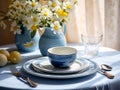 table with elegant vase with flowers and ceramic plates in white-blue colors Royalty Free Stock Photo