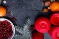 On the table are a few candles, a twig of afir-tree and a white plate with cranberries. Top view. Close up.