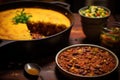 A table is filled with a variety of bowls of food and an enticing pie, A piping hot pot of chili with a side of cornbread, AI