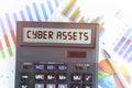 On the table are financial charts and a calculator, on the electronic board of which is written the text - CYBER ASSETS Royalty Free Stock Photo