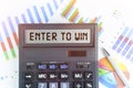 On the table are financial charts and a calculator, on the electronic board of which is written the text - ENTER TO WIN