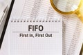 On the table are financial reports, a pen, a magnifying glass and a notebook with the inscription - FIFO