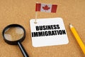 On the table is the flag of Canada, a pencil and a sheet of paper with the inscription - Business immigration