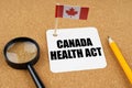 On the table is the flag of Canada, a pencil and a sheet of paper with the inscription - Canada Health Act