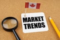 On the table is the flag of Canada, a pencil and a sheet of paper with the inscription - market trends