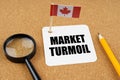 On the table is the flag of Canada, a pencil and a sheet of paper with the inscription - market turmoil