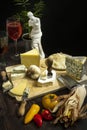 A table full of delicious assorted cheeses with knives, tomatoes,