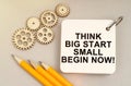 On the table are gears, pencils and a notebook with the inscription - Think Big Start Small Begin Now Royalty Free Stock Photo