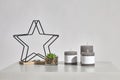 Table with green succulent, three different sized candles, one small in candlestick in form of iron star on wooden stand Royalty Free Stock Photo