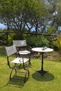 Table and iron chairs on green grass in the garden