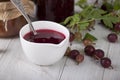 On the table area white bowl of homemade red gooseberry jam Royalty Free Stock Photo