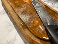 Table knife with a black handle on a wooden kitchen board. Dirty knife after cutting mozzarella cheese and tomatoes. Tomato seeds Royalty Free Stock Photo