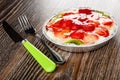 Knife and fork, pie with slices of strawberry and kiwi in mold from foil on wooden table Royalty Free Stock Photo