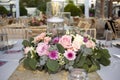 A table with a large centerpiece of pink and white roses