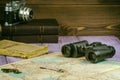 On the table lay an old book, map, coins, a key and a pair of binoculars. Also there is a film camera.