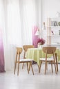 Table with lemon water, fresh heather and green tablecloth in real photo of dining room interior with lamps, window Royalty Free Stock Photo