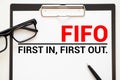 On the table lies a smartphone, a calculator and a notebook with the inscription- FIFO. First In, First Out