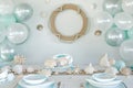 table with life ring wall decor, white and light blue balloons, and shellshaped dishes