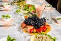 Table lined with variety of dishes from which the centerpiece is dish with sliced fruit