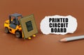 On the table, the loader transports the processor, next to it is paper with the inscription - Printed Circuit Board