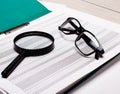 On the table are a magnifying glass, colored reports, and black-framed glasses. Banner. Business concept