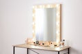 Table with makeup products and mirror near white wall, space for text. Royalty Free Stock Photo
