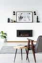 Table next to grey armchair in white loft interior with poster a Royalty Free Stock Photo