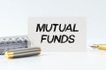 On the table is a notebook, a pen and a business card with the inscription - MUTUAL FUNDS