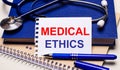 On the table are notepads, a stethoscope, a pen and a sheet of paper with the text MEDICAL ETHICS. Medical concept Royalty Free Stock Photo