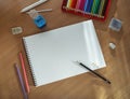 On the table is an open sketchbook, a set of colored pencils, erasers and a sharpener. Empty space for text on the album sheet. Royalty Free Stock Photo