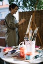 Table with paint tubes and brushes in front of blurred artist Royalty Free Stock Photo