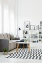 Table on patterned carpet in modern living room interior with gr