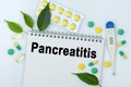 On the table are pills, a thermometer, leaves and a notebook with the inscription -Pancreatitis Royalty Free Stock Photo