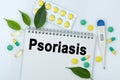 On the table are pills, a thermometer, leaves and a notebook with the inscription -Psoriasis Royalty Free Stock Photo