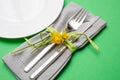 Table place setting in bright green. Gray linen napkin and white plate on green color background