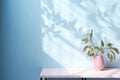 Table with plant in vase against blue wall background. Generative AI Royalty Free Stock Photo